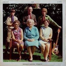 A group of six people posing outdoors with an electric guitar on a vinyl cover.