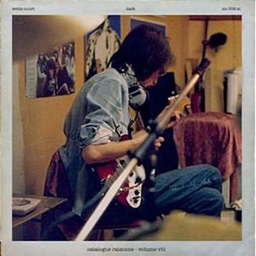 Man playing a red and white electric guitar in a room.