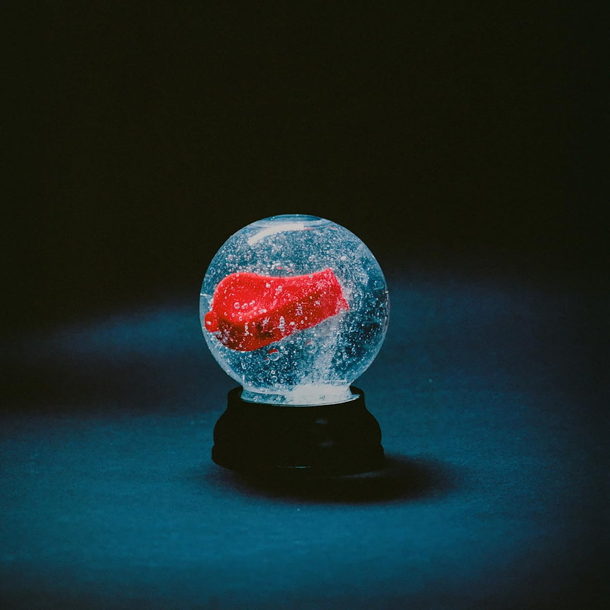 Snow globe containing a red, abstract shape against a dark background.