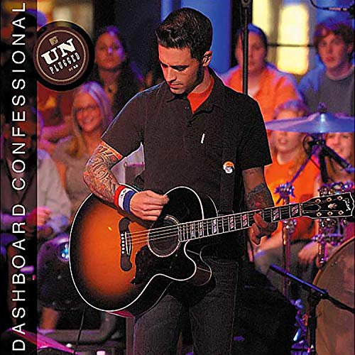 The image shows a man playing an acoustic guitar on stage, with a blurred audience.
