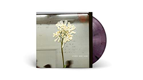 Vinyl record cover featuring a white flower against a blurred background with purple vinyl.