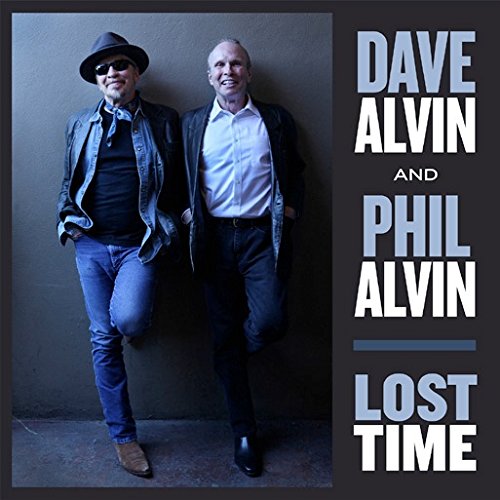 Dave and Phil Alvin standing side by side against a dark wall.