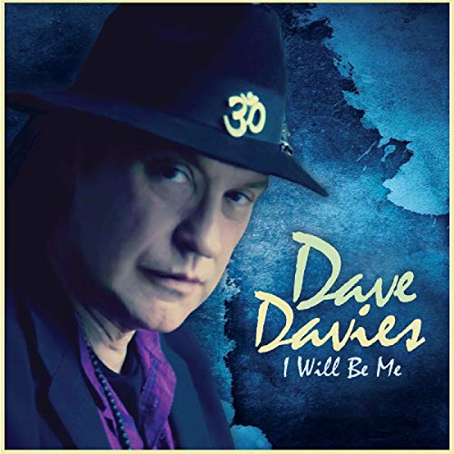 Dave Davies wearing a hat with an Om symbol on a blue textured background.