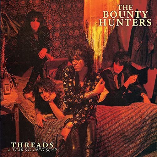 Album cover featuring four people in a dimly lit, ornate room.