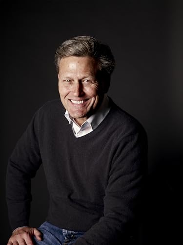 Man with short gray hair smiling at the camera, wearing a sweater.