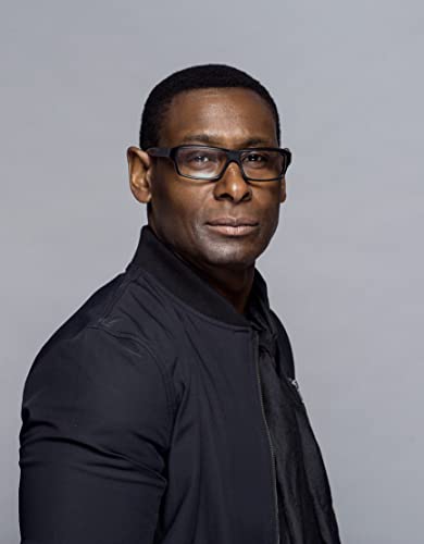 Close-up portrait of a Black man wearing glasses and a black jacket.