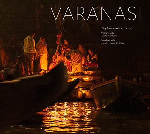Varanasi at night: people with candles on boats on the water.