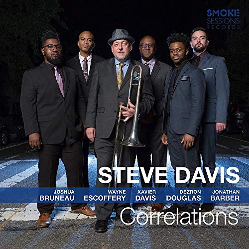 Six men in suits stand on a crosswalk at night, one holding a trombone.