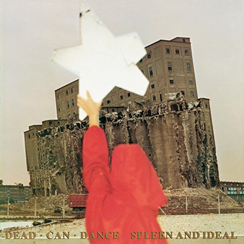 Red-clad figure holds white stars before a crumbling concrete building.