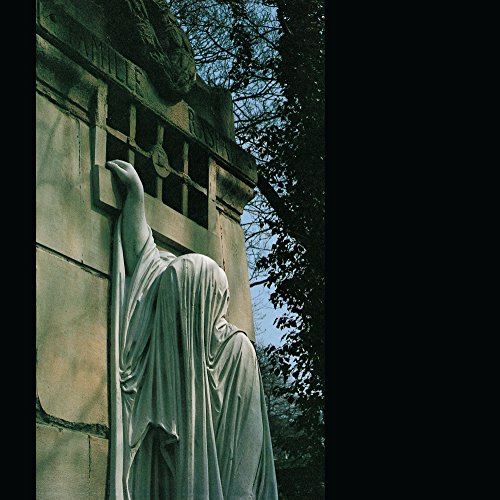 A stone statue of a robed figure against a stone building.