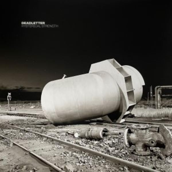 A large industrial tank sits on train tracks in a desolate, dark landscape.