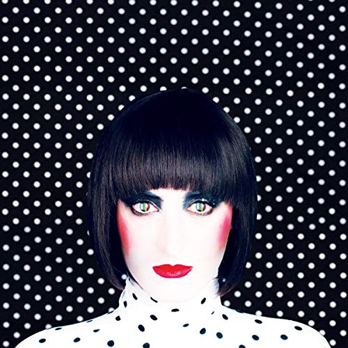 A woman with a black bob and red lipstick against a black polka-dot background.
