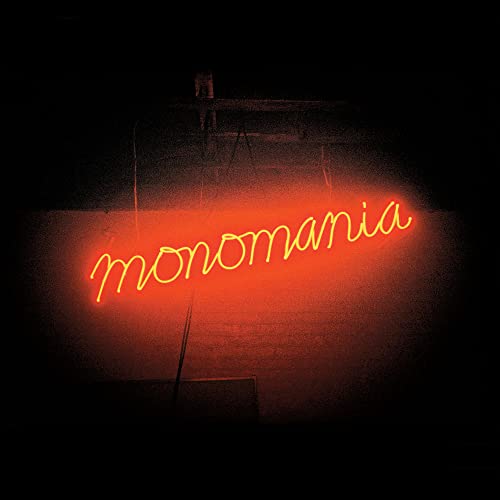 Red neon sign spelling "monomania" against a dark, textured background.