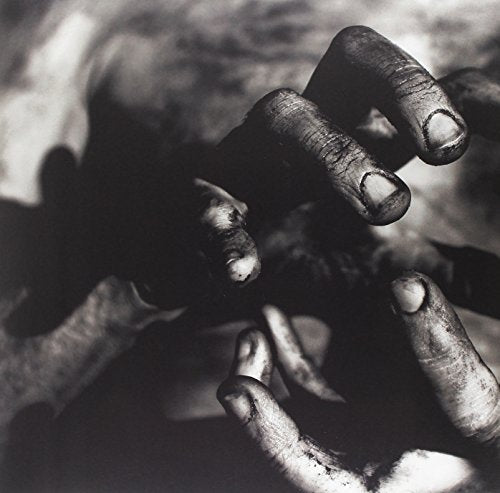 "Black and white image of dirty hands reaching towards each other."