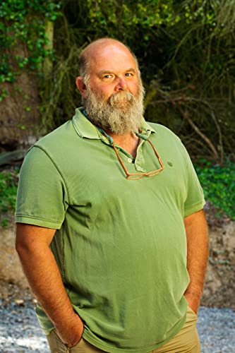 Bearded man in green polo shirt stands outdoors, looking at viewer.
