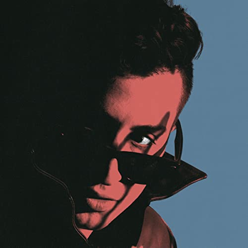 A person in sunglasses with red lighting against a dark and blue background.