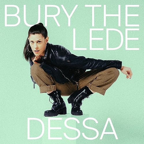 Person in a leather jacket and boots crouching against a mint green background.