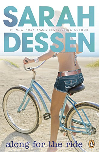 A young woman rides a light blue bicycle on a sandy beach.