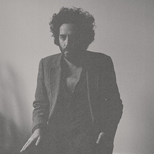 Black and white portrait of a man with curly hair in a suit.