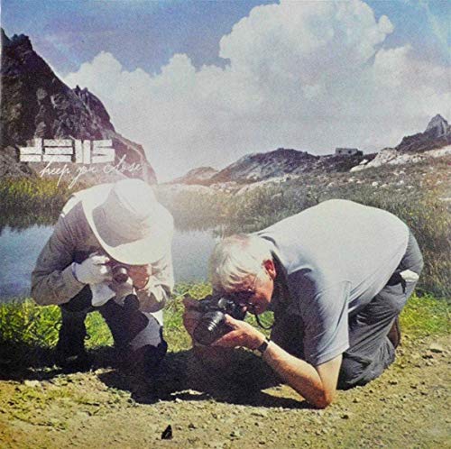 Two older men with a camera in a mountainous landscape.