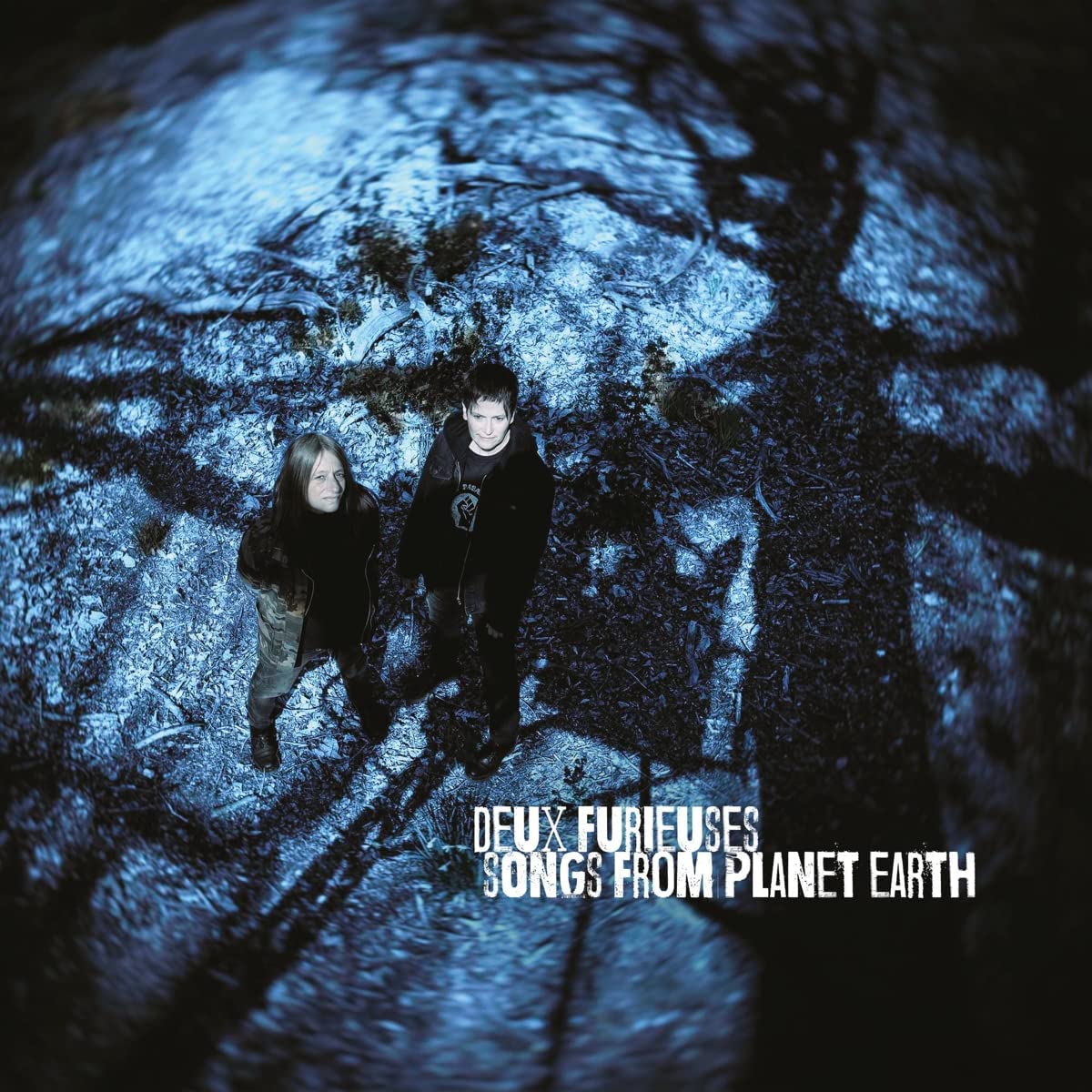 "Album cover with two people standing on a textured, blue-gray surface, text at bottom."
