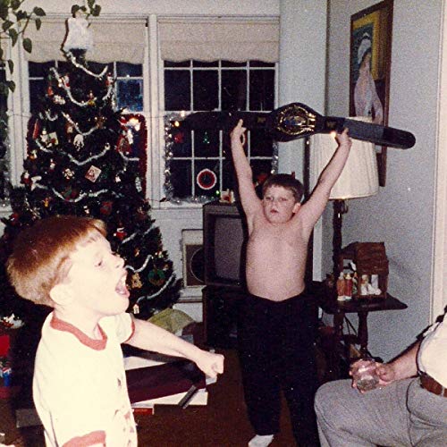 A young boy holds a wrestling belt aloft in a decorated living room.