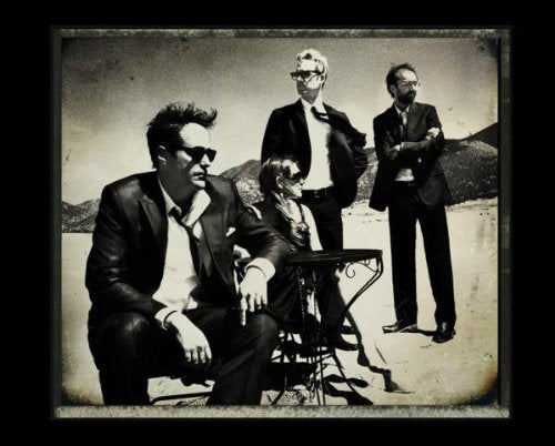 Black and white photo of four people in suits and sunglasses.