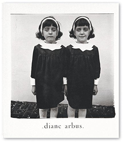 Black and white photo of identical twin girls in dark dresses.