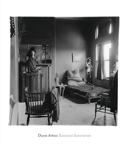 Black and white photograph of a sparse room containing a bed and mannequin head.