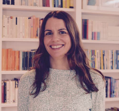 Woman smiling, with books blurred in the background.