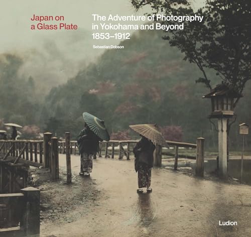 Vintage photograph of two figures with umbrellas on a Japanese road.