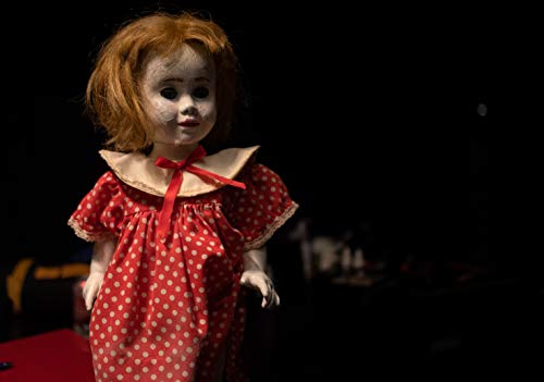 Vintage doll with red dress and curly hair, darkly lit.