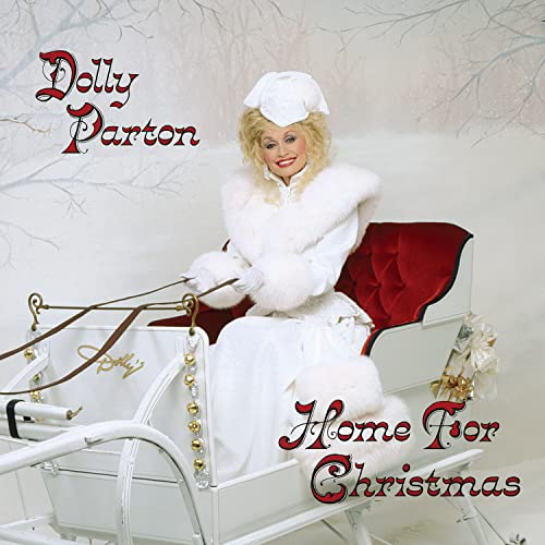 Dolly Parton in a white coat and hat, sitting in a sleigh.