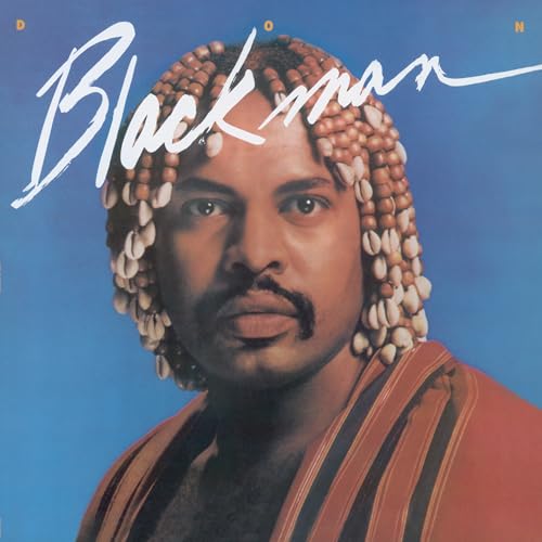 Portrait of Don Blackman with beaded hair against a solid blue background.