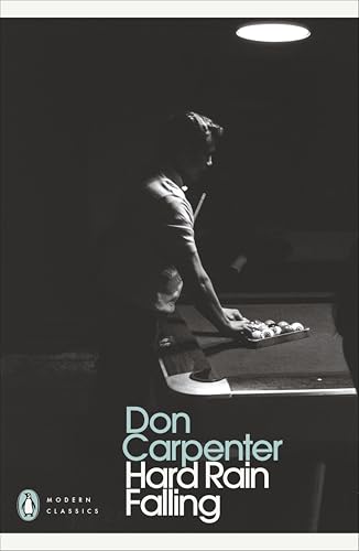 A man in a dark room leans over a pool table under a spotlight.