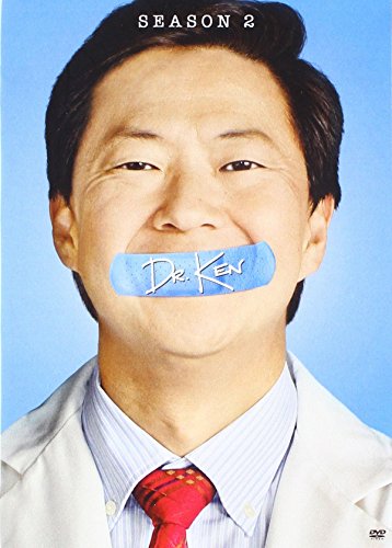 Ken Jeong wearing a lab coat with a blue bandage over his mouth.