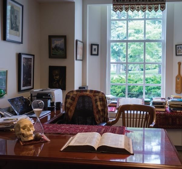 Desk with open book, skull, and view through a multi-paned window.