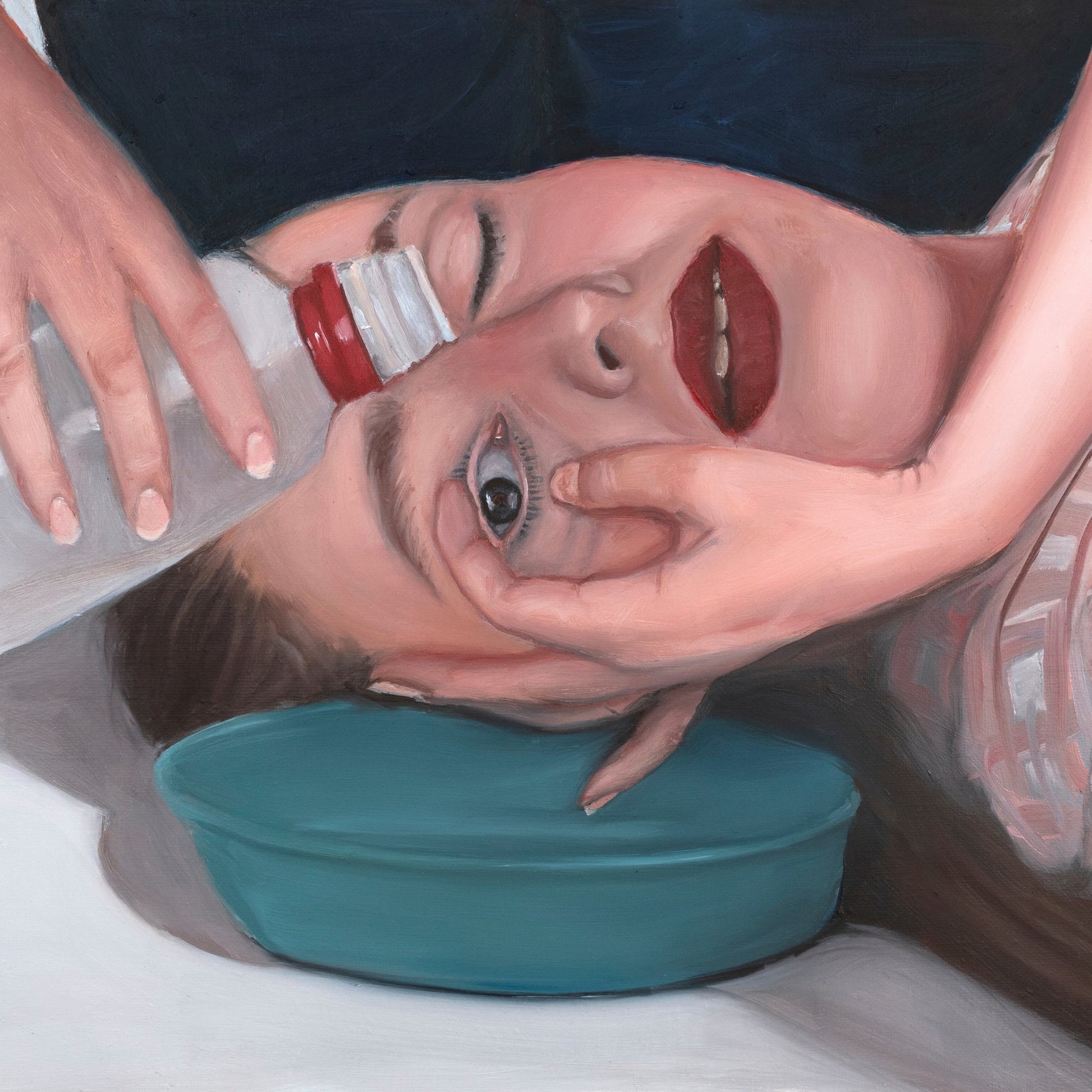 Painted face with red lips, hands holding cheeks, teal object below.