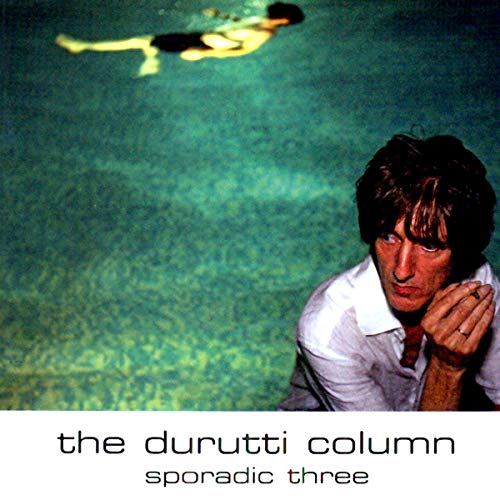 A man sits by a pool where a person is swimming underwater.