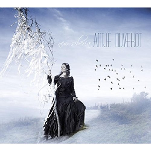 CD cover: woman in black dress stands near a bare tree, birds flying.