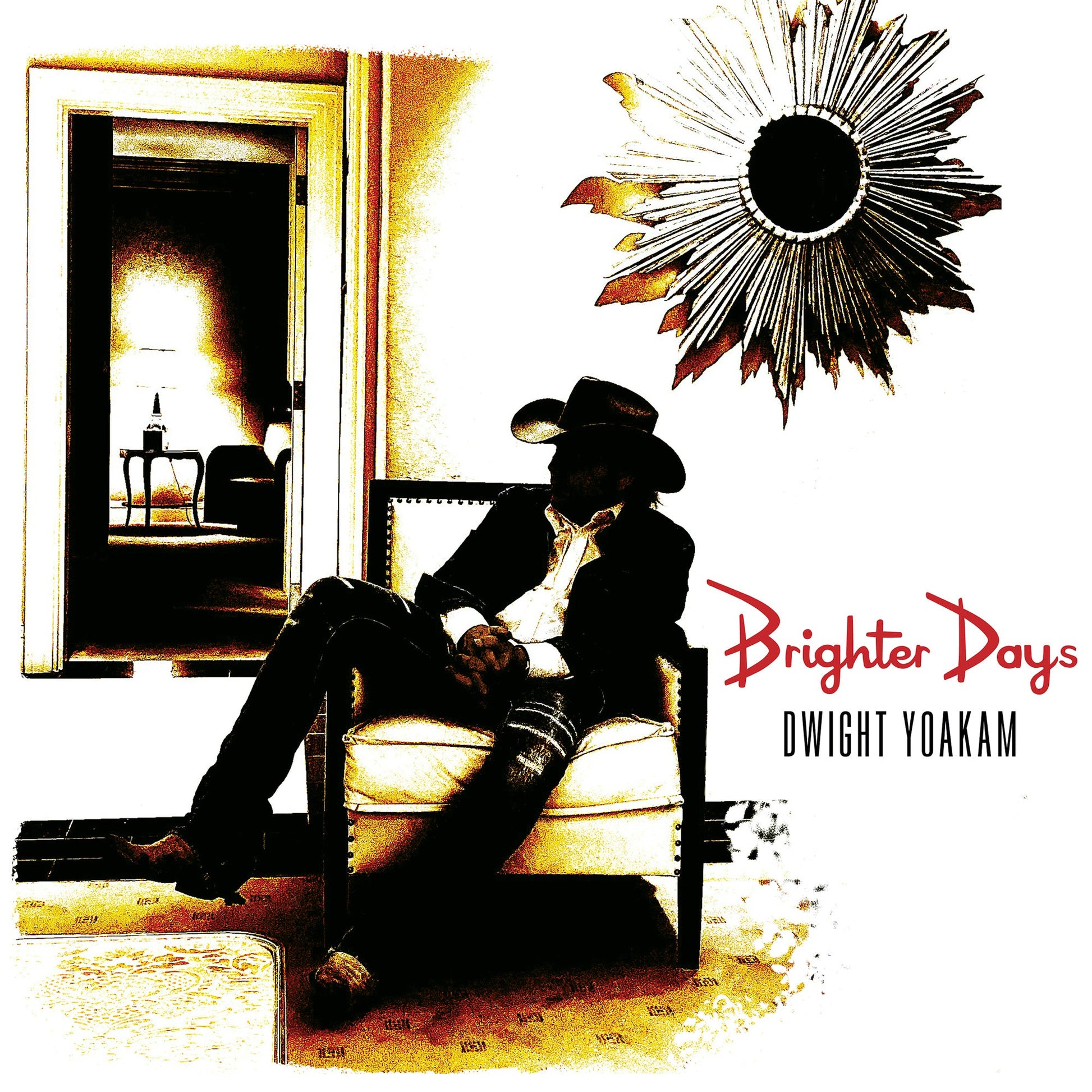 Dwight Yoakam sits in a chair in a room with a sunburst mirror above.