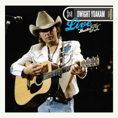 Dwight Yoakam wearing a cowboy hat and playing an acoustic guitar on stage.