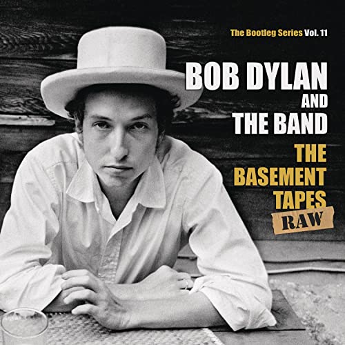 Black and white photo of Bob Dylan in a hat with album text overlay.