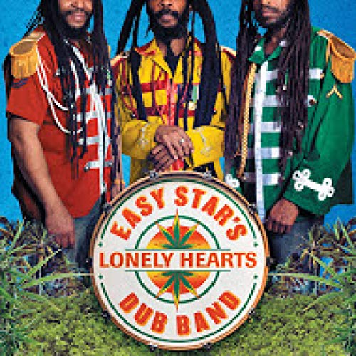 Three dreadlocked musicians with a circular band logo in front.