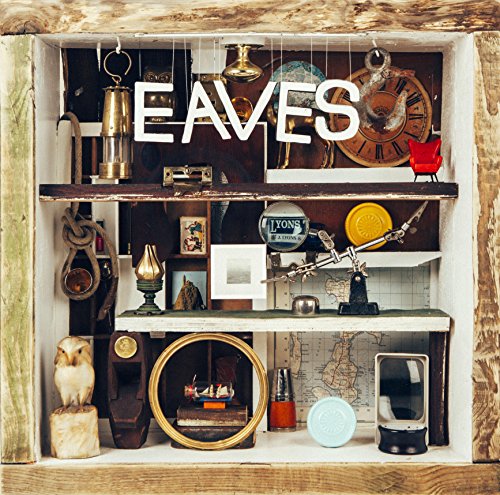 A wooden shelf with various eclectic objects and the word "EAVES" in white letters.