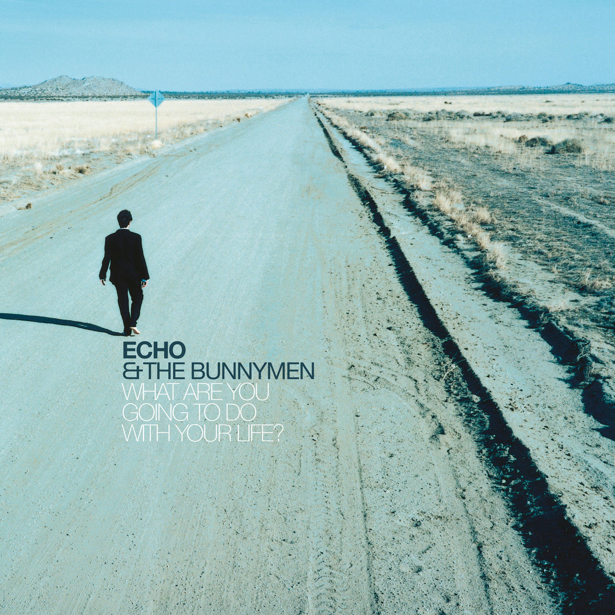 Album cover: man walking down a long, empty desert road.