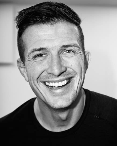 Black and white portrait of a smiling man with short dark hair.