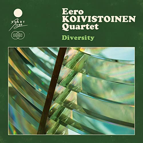 CD cover with green background, text, and a close-up of iridescent glass lens segments.