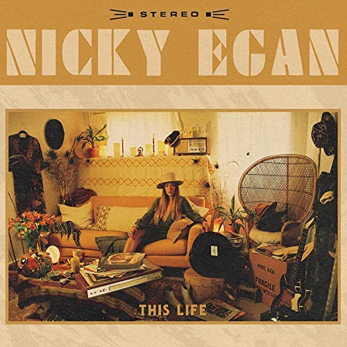 Vinyl record cover: woman with guitar in a cluttered room.