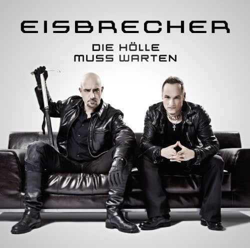 Two men in leather jackets sit on a brown couch.